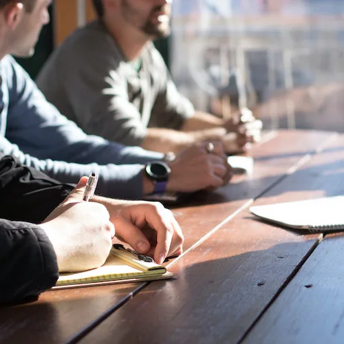 People in a meeting with notebooks>